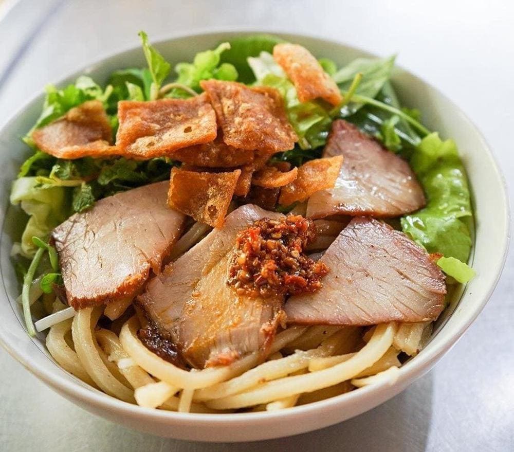 Thick Hoi An noodles with pork slices and herb garnishes